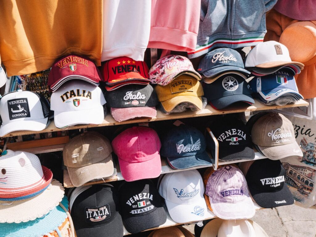 Assortment of colorful Venezia and Italia caps on display in Venice, Italy market.