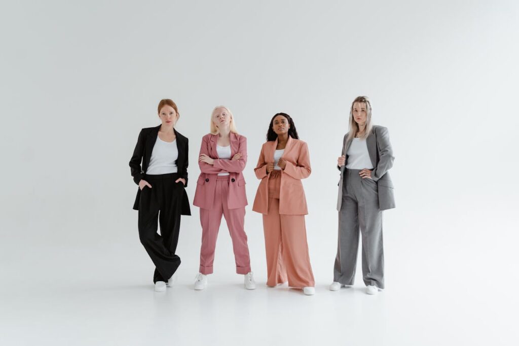 Four diverse women confidently posing in stylish suits against a plain white background.