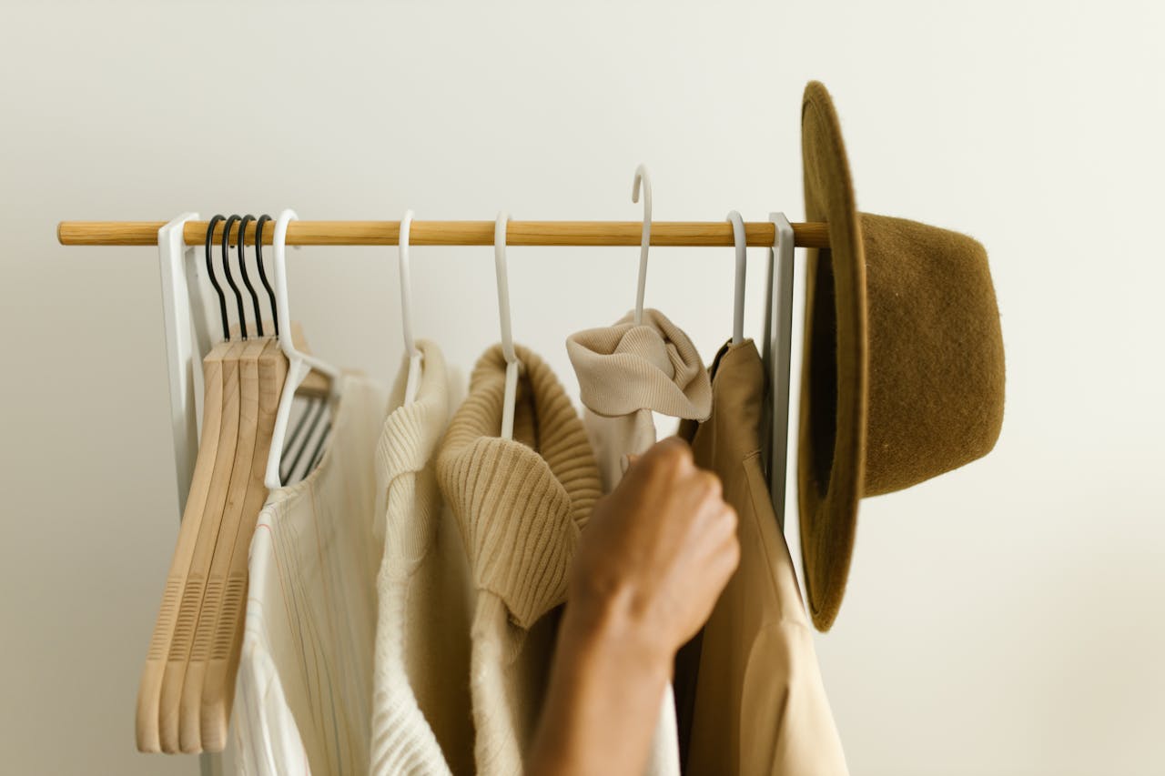 Mastering the First Impression: Your intriguing post title goes here Stylish beige and brown clothes on a rack with a hand reaching in.